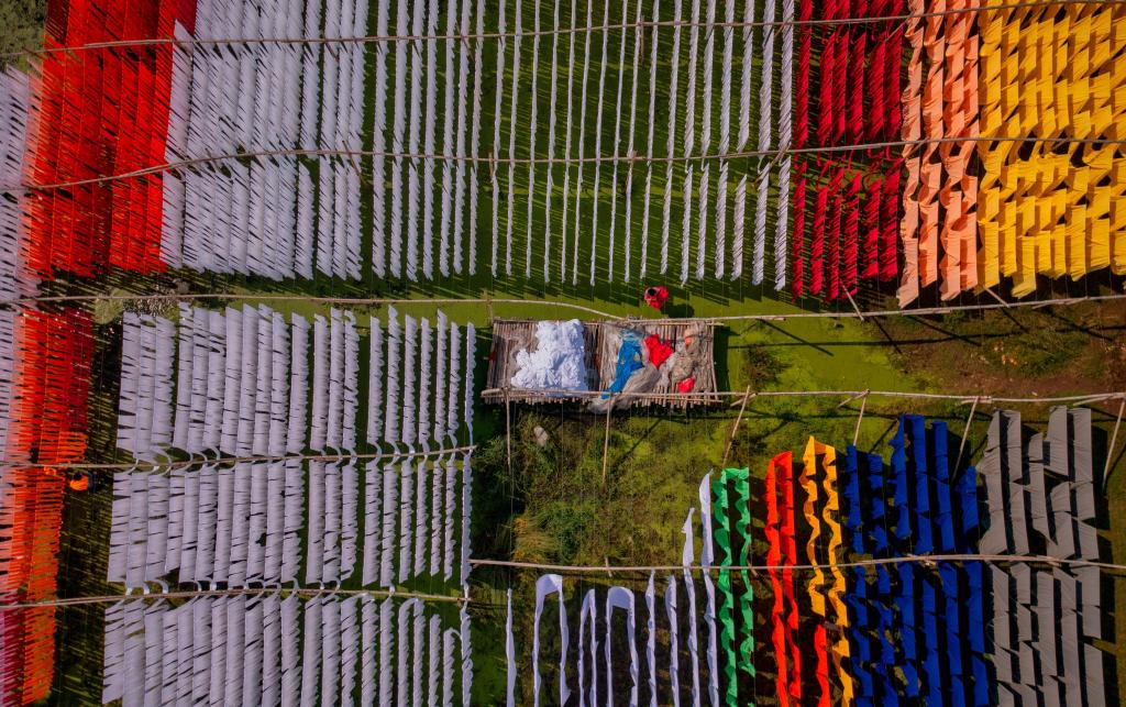 Aerial view of people working in an open-air laundry with colourful fabric hanged to dry in Narayanganj, Bangladesh. 
