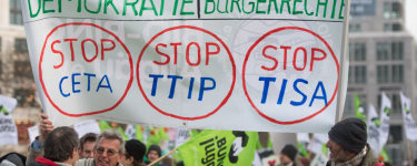 Protestors hold a Stop CETA, Stop TTIP and Stop TISA banner.