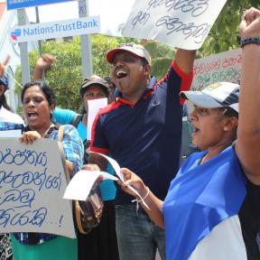 Members of War on Want partner trade union FTZ&GSEU in Sri Lanka, protesting in defence of the right to strike, with fists raised and shouting chants.