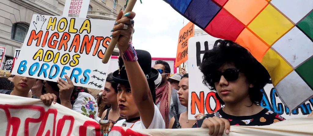 Latin American people on a march in London waving the Wiphala flag. One placard reads "Hola migrants, adios borders". Photo: David Sandison