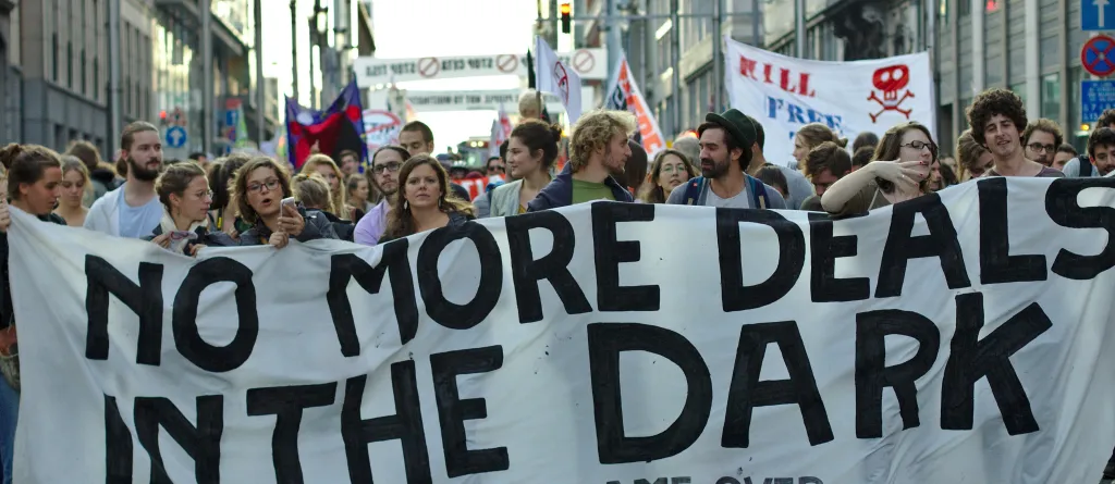 Protest in Brussels against the TTIP and CETA free trade agreements. Protesters hold a banner that says "No more deals in the dark. TTIP game over." Photo: M0tty