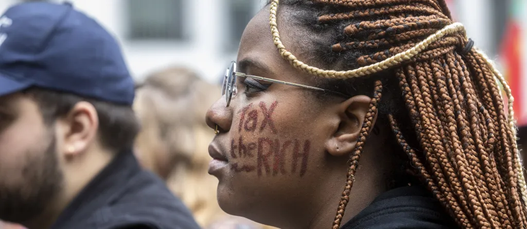 Profile of a woman with 'Tax the Rich' written on her face