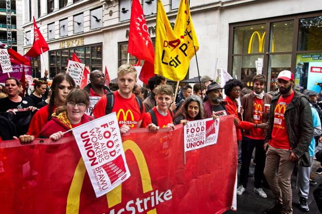 Young striking McDonald's workers take action outside a McDonald's restaurant. They are behind a red McStrike banner that also shows the Bakers Food and Allied Workers Union logo. Credit: Garry Knight