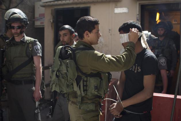 Palestinian man being arrested and blindfolded by Israeli soldier