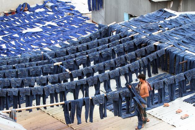 A worker collects pairs of dyed jeans from rooftops in Dhaka, Bangladesh, July 2014. 
