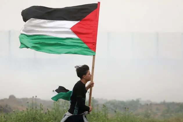 Boy runs with Palestinian flag