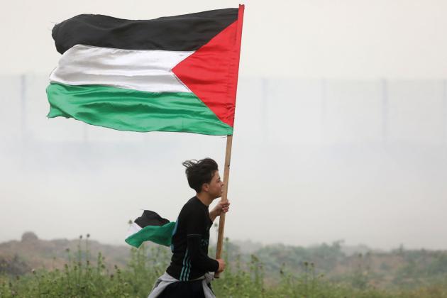 Boy runs with Palestinian flag