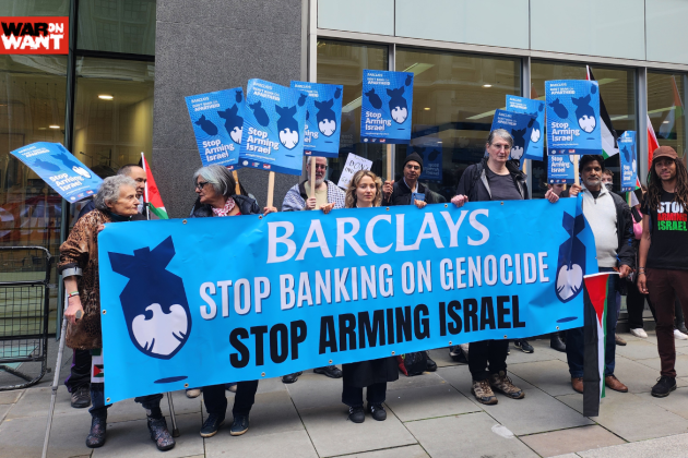 Group of people hold a blue banner which says 'Barclays: Stop banking on genocide, stop arming Israel'