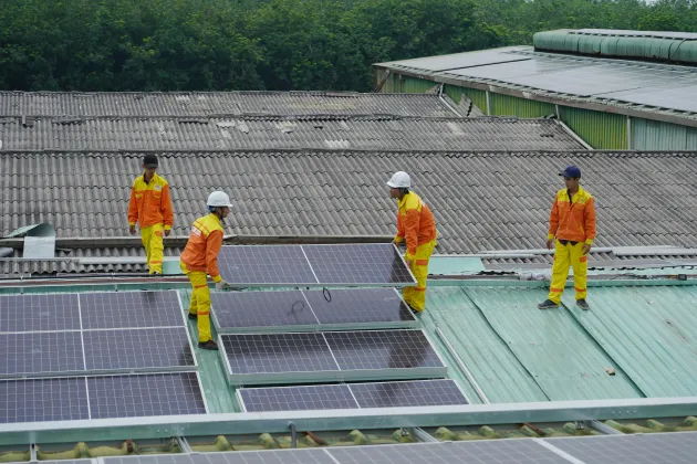 Workers fixing solar panels onto a roof.