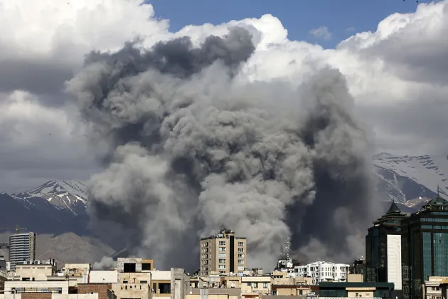 Grey smoke billowing behind buildings