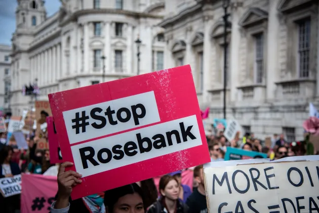 A red sign that has the words '#StopRosebank' on it. Someone is holding the sign during a climate protest.