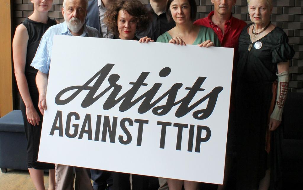 A group of 8 people hold a large sign that reads "Artists against TTIP".