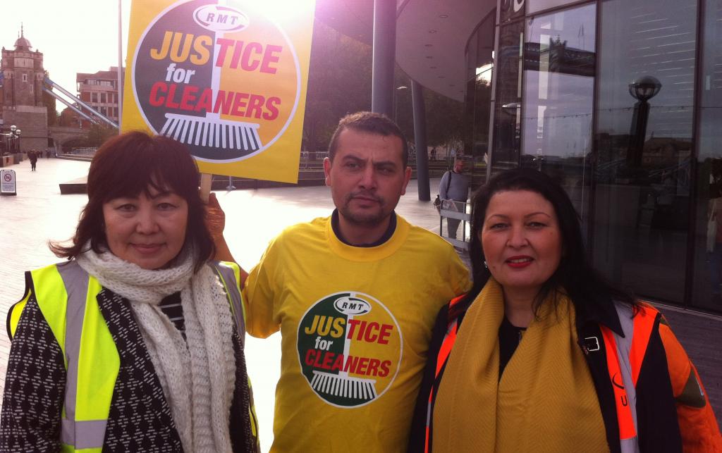 Three people protesting, two wear hi-vis and other other has a yellow T-shirt and placard that both read "RMT Justice for Cleaners".
