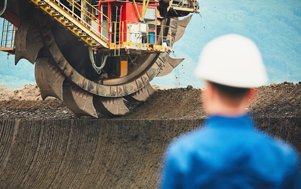 Miner looking at huge excavator in the Czech Republic