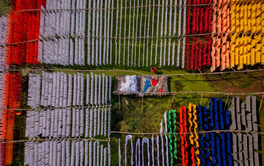 Aerial view of people working in an open-air laundry with colourful fabric hanged to dry in Narayanganj, Bangladesh.