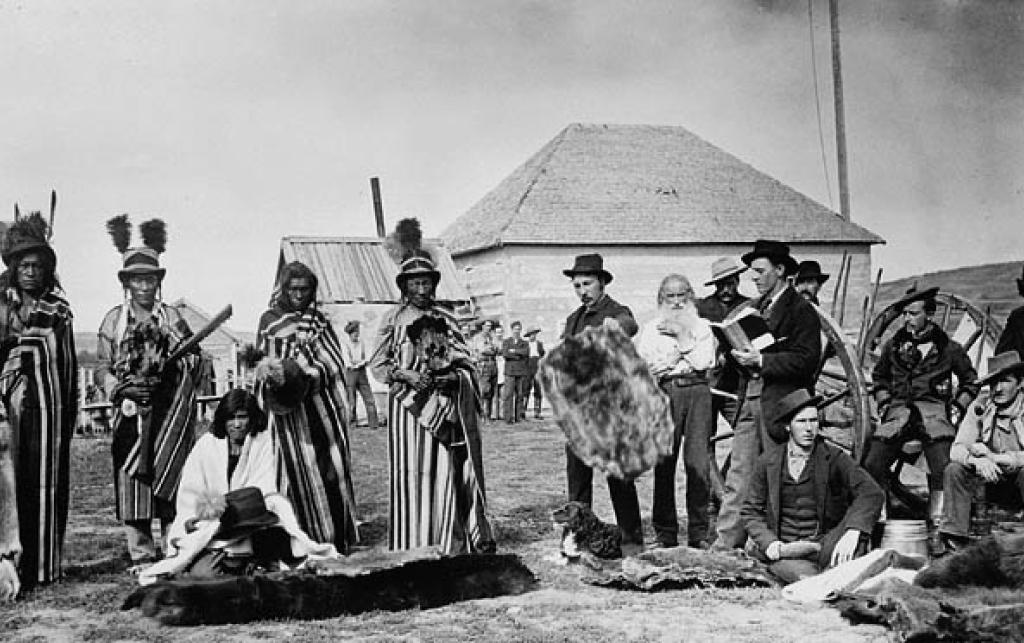 Mistahi maskwa (Big Bear (standing forth from left) a plains Cree chief trading furs at Fort Pitt, Northwest Territories, 1884.