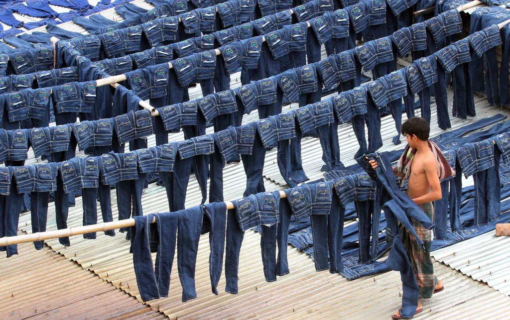 A worker collects pairs of dyed jeans from rooftops in Dhaka, Bangladesh, July 2014. 