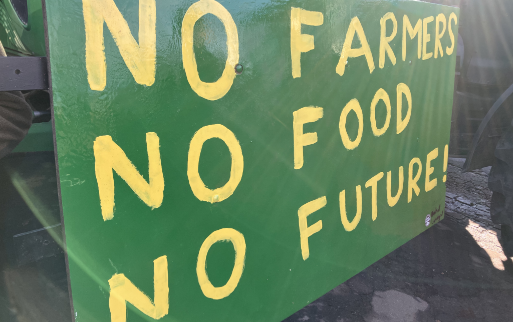 A green board which has 'No farmers, no food, no future' painted on it in yellow paint.