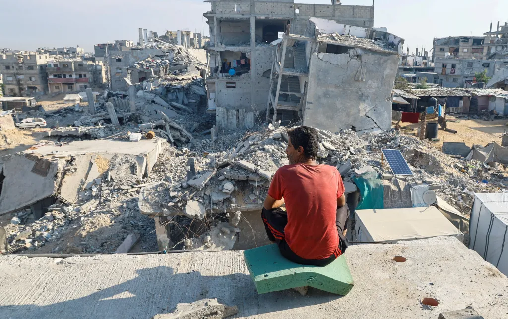 A Palestinian man sits on the rubble of a house destroyed by Israeli military attacks, in Khan Younis in the southern Gaza Strip
