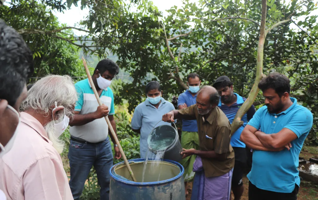 A group of men pouring water into a barrel