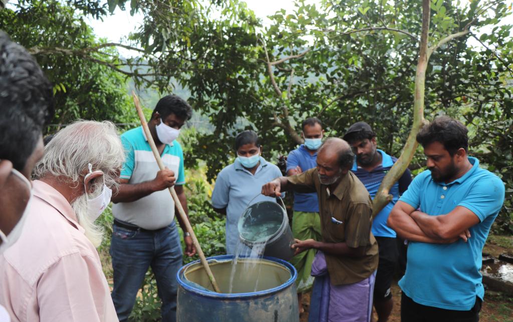 A group of men pouring water into a barrel