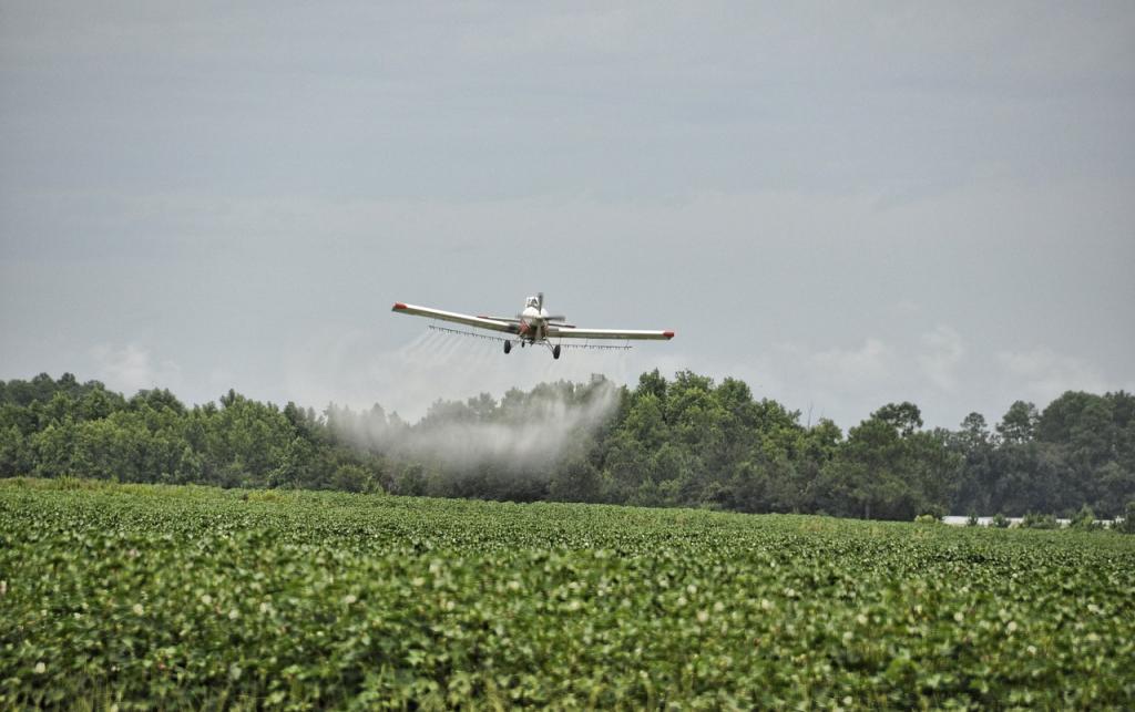 Airplane spraying pesticides over land with bright green plants