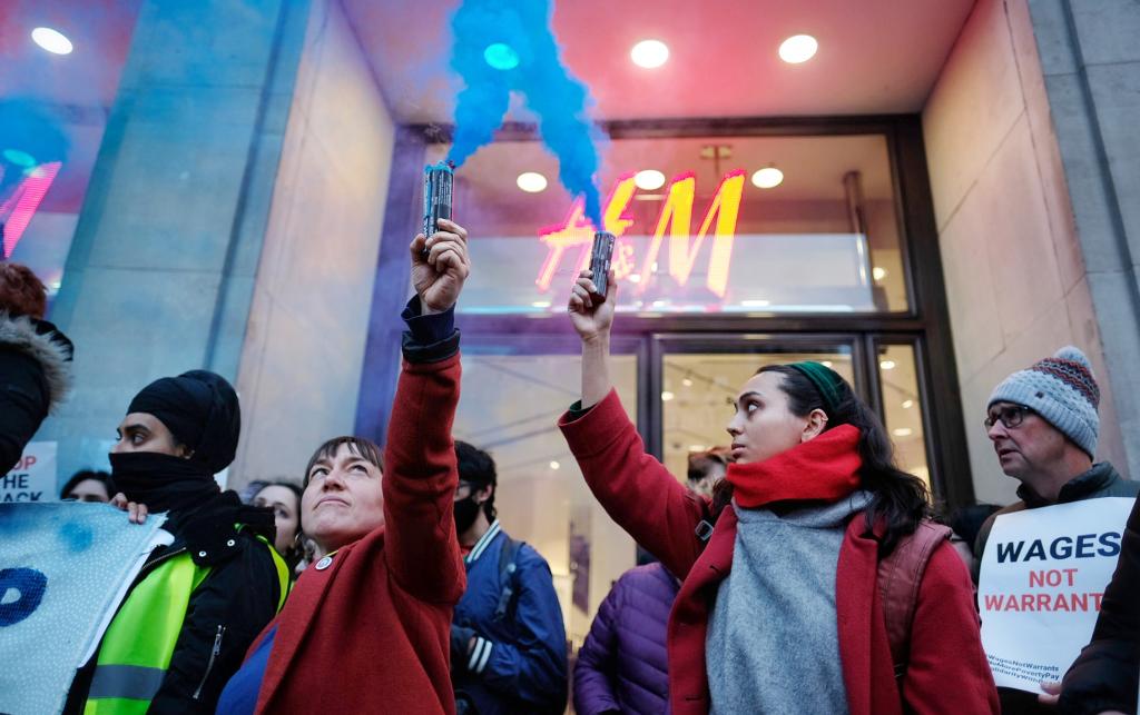 Two women holding up bright blue flares in the air.