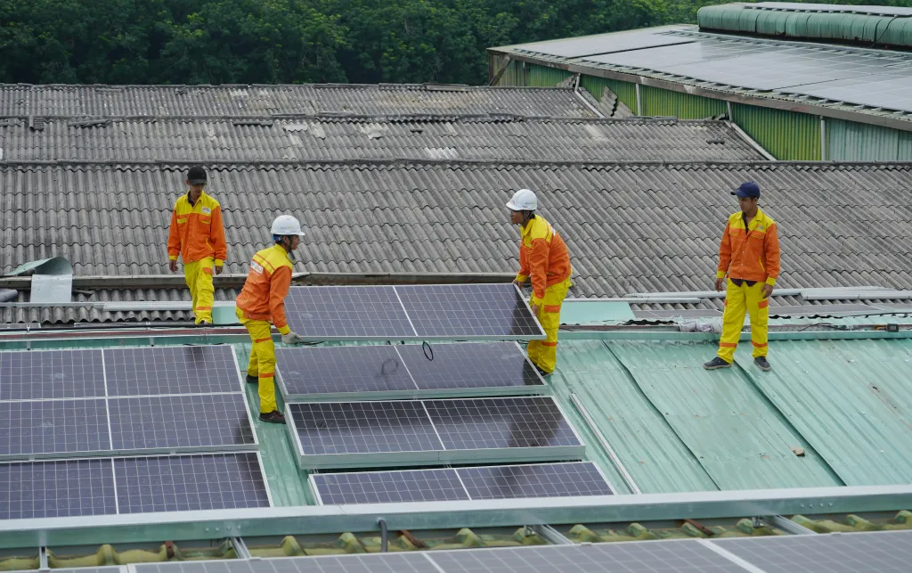 Workers fixing solar panels onto a roof.
