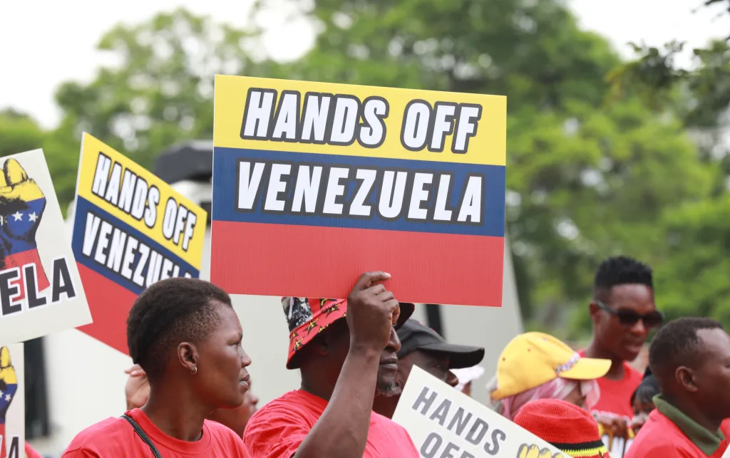 Protestor holds banner saying 'HANDS OFF VENEZUELA'.