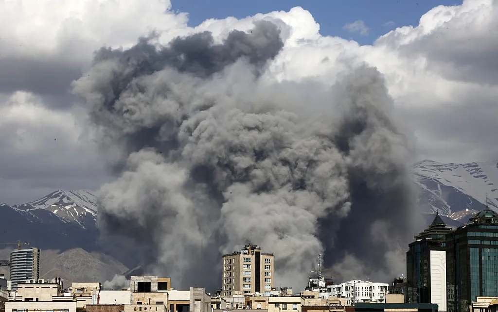 Grey smoke billowing behind buildings