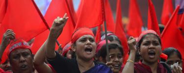 Women protest at a May Day Demonstration, with red headbands and flags. Dhaka, Bangladesh. Credit: MUNIR UZ ZAMAN / AFP / Getty Images