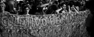 Black and white photo of Brazilian protestors holding a banner that says "Coletivo Feminista Classista Ana Montenegro". Photo: fabio montarroios CC BY 2.0
