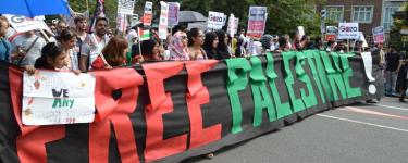Protesters hold a large batter that reads "Free Palestine!" at a demonstration.