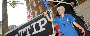 At a #NoTTIP demonstration, two protestors roleplay a businessman holding an NHS nurse as a marionette. Photo: War on Want
