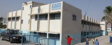 A UNRWA school with children walking by outside. The sign on the front of the building reads: "UNRWA North Amman Area, Department of Education, Baq'A Elem. Boys School no. 3&4. Photo: خليل مزرعاوي, / Addustour, Jordan Press & Publication Co. http://addustour.com/
