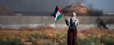 Women holding Palestiniain flag at apartheid wall