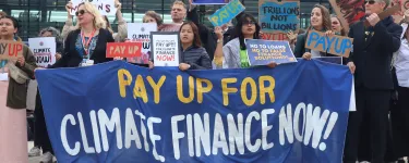 Campaigners hold a large banner which reads 'Pay up for climate finance now!'