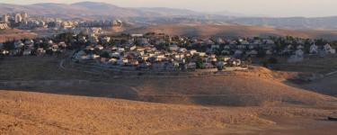 An Israeli settlement, buildings in the distance across the desert.