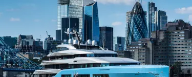 Large yacht in Thames river in front of city of London.