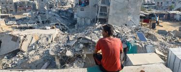 A Palestinian man sits on the rubble of a house destroyed by Israeli military attacks, in Khan Younis in the southern Gaza Strip