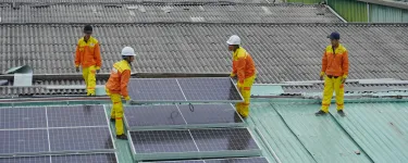 Workers fixing solar panels onto a roof.