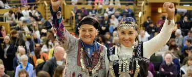 Two people stand with their arms up in front of a crowd