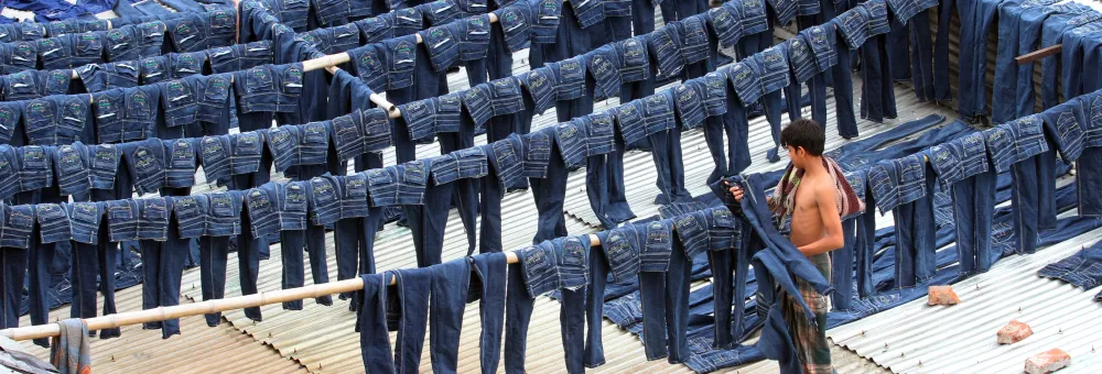A worker collects pairs of dyed jeans from rooftops in Dhaka, Bangladesh, July 2014. 