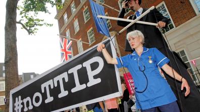 At a #NoTTIP demonstration, two protestors roleplay a businessman holding an NHS nurse as a marionette. Photo: War on Want