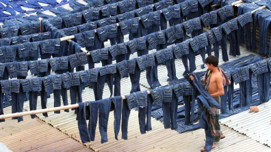 A worker collects pairs of dyed jeans from rooftops in Dhaka, Bangladesh, July 2014. 