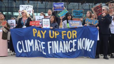 Campaigners hold a large banner which reads 'Pay up for climate finance now!'