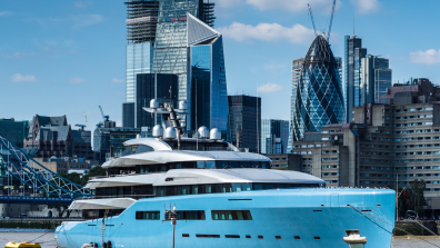 Large yacht in Thames river in front of city of London.