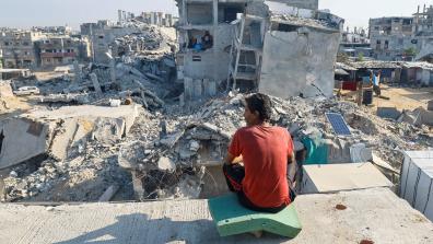 A Palestinian man sits on the rubble of a house destroyed by Israeli military attacks, in Khan Younis in the southern Gaza Strip