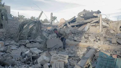 Man surrounded by rubble in the Gaza Strip, bending down to move a piece with his hands
