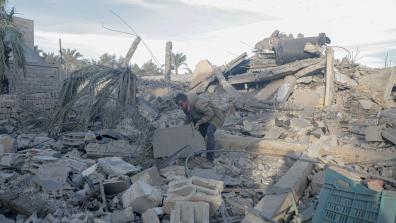 Man surrounded by rubble in the Gaza Strip, bending down to move a piece with his hands